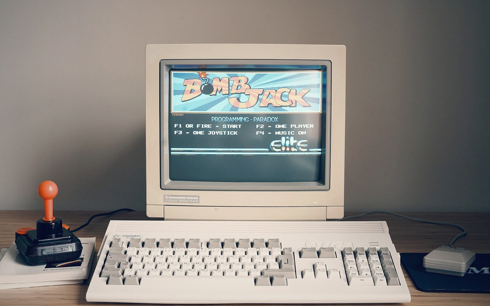 Commodore 64 monitor displaying the Bomb Jack title screen beside a keyboard and joystick