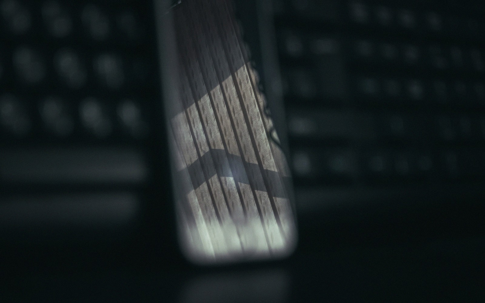 Close-up of a smartphone with wood-grain patterned back propped against a computer keyboard